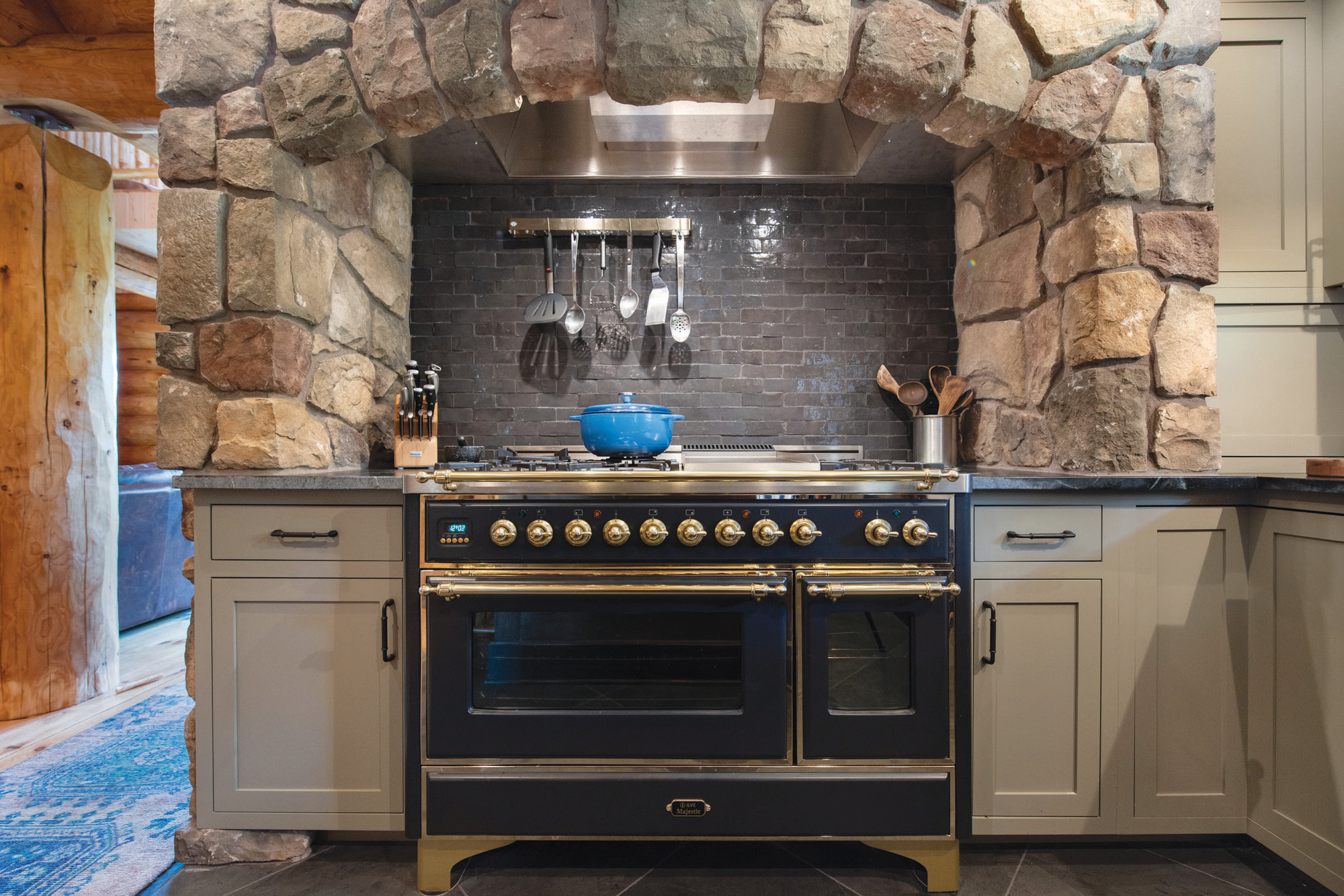 A handmade backsplash blends with the stone arch above a 48-inch, French-style range in this Spokane kitchen.