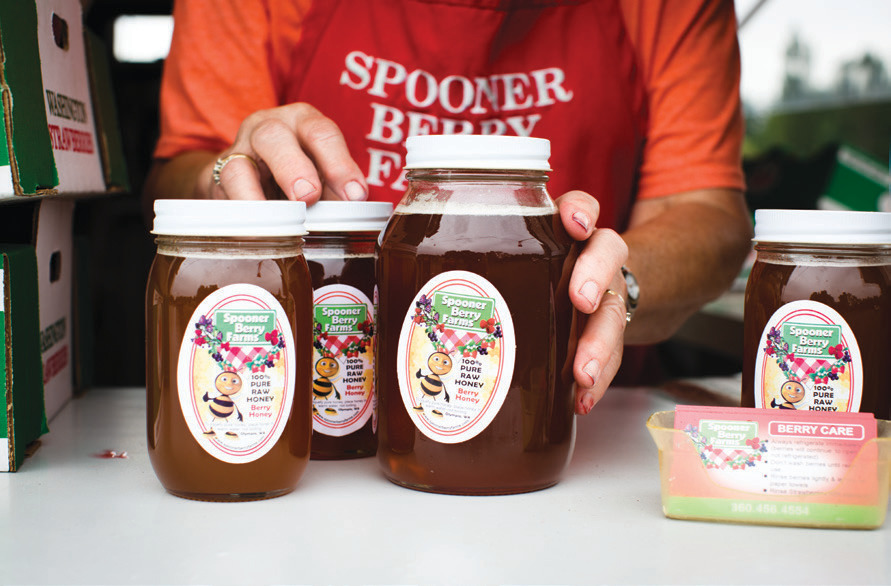 A beekeeper tends to bees on the farm, which help pollinate the berries and produce the farm’s best-selling berry honey.